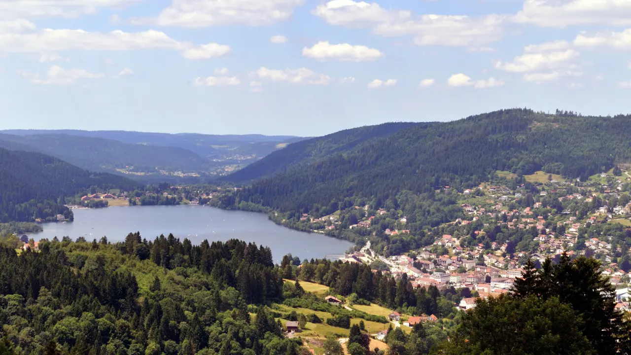 Vue panoramique du lac de Gérardmer entouré de forêts et de montagnes vosgiennes, illustrant un site naturel propice à la baignade, aux randonnées et aux activités de plein air en 2026.
